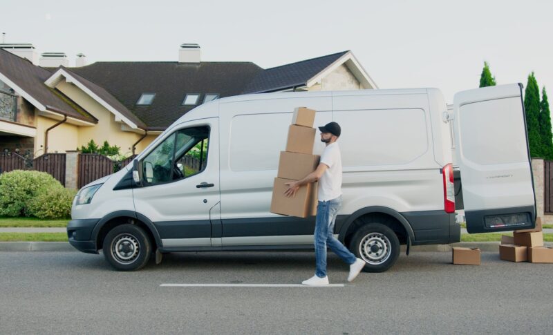 man carrying boxes beside a van